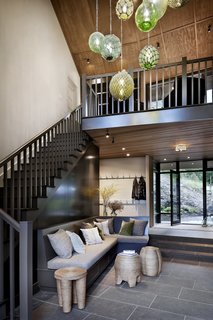 The hallway pendant was another custom design made by Decorative Metal Arts with vintage glass buoys sourced from Along Shores Décor. "The panels behind the banquette seating in the stair hall are magnetic, so people can leave notes about their plans for meeting up or for outdoor adventures, or just as a place to exchange pleasantries," adds DeForest.