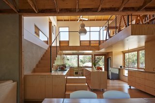 A section of the kitchen countertop wraps around the end of the stairs and serves as a landing. The washer/dryer are concealed behind the doors of that unit.