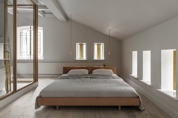 If you’re working with a room that has sloped or low ceilings, a ground-hugging bed frame allows for ample head height and takes advantage of windows that might sit close to the ground, like at this converted horse stable in Copenhagen. Here, Danish design reigns supreme: soap-washed pine flooring is consistent throughout the home, but the darker wood finishes on a custom bed frame made out of oiled white Douglas fir allow it to stand out.