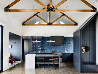 Although strikingly different from its traditional farmhouse exterior, the interiors reference the outer appearance with an exposed solid granite wall in the living room and exposed roof trusses with black plated junctions that recall the artisanal joinery and construction techniques found in traditional Japanese homes.