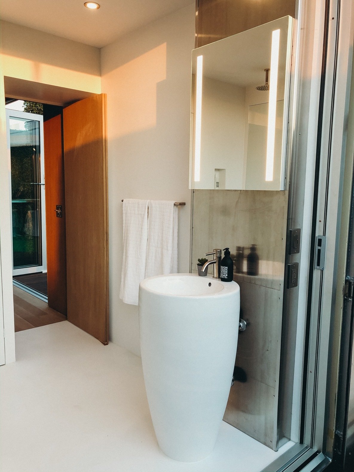 A Fine Fixtures pedestal sink is placed near a space-saving Kohler Verdera medicine cabinet and a Toto Legato toilet.