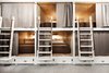Modern home with Bedroom, Concrete Floor, Bunks, Wall Lighting, and Storage. The bunk beds were built from painted millwork, beadboard, and plywood with walnut handrails and unlacquered polished brass hardware. Sturdy, ergonomic ladders provide access to the top bunks. Photo 4 of Cache House