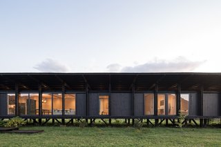 The elevated modular home is clad in locally sourced radiata pine treated with a stone-gray oil stabilizer.