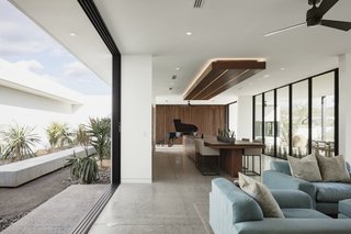 Pocketing glass doors on either side of the main living space can be completely opened for cross ventilation. The blue living room sofas are from Feathers Fine Custom Furnishings.