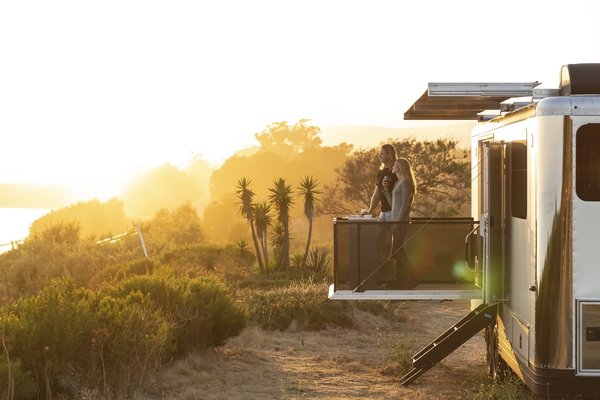 Living Vehicle founders Joanna and Matthew Hoffman seen standing on the seven-foot-deep patio deck that folds down and sets up from the side of the vehicle in less than a minute.