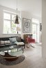 Modern home with Living Room, Sofa, Chair, Bookcase, Coffee Tables, Pendant Lighting, and Light Hardwood Floor. More color is found in the living area's tapestries, including a round rug and multiple sofa pillows. A contemporary brass and glass pendant light hangs above the glass coffee table. Photo 11 of Colorful & Eclectic Danish Home