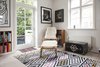 Modern home with Living Room, Chair, Bookcase, and Light Hardwood Floor. Bamboo chair with fur throws sits atop yellow, pink, and black diamond patterned rug near a black antique chest. Photo 9 of Colorful & Eclectic Danish Home