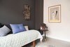 Modern home with Bedroom, Bed, Night Stands, and Medium Hardwood Floor. Bedroom with mint quilt, slate colored wall, and peace sign lighted art Photo of Minimalist Nordic Flat