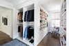 Modern home with Storage Room, Closet Storage Type, Shelves Storage Type, and Cabinet Storage Type. All-white cabinetry offers a crisp look that allows your clothing to steal the spotlight. The high-contrast shaker style doors, create an elegant backdrop for your clothing. Light also pours through the big windows, drawing your eye to the iconic views of the Hudson River. It creates a feeling of brightness and positivity that energizes and enlivens. It’s a walk-in closet where you can look and feel your best as you begin your day.
For added visual appeal, the unit was accented with crown and base molding. The elegant detailing was inspired by the pre-war era building’s architectural features. The moldings add a retro geometric touch that matches the apartments beamed ceilings and traditional herringbone floors that were all the rage during the period and make a striking comeback in this beautiful renovation. Photo 2 of Crisp White Walk-In Closet