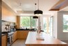 Modern home with Kitchen, Range Hood, Stone Counter, Concrete Floor, Pendant Lighting, Undermount Sink, and Wood Cabinet. Kitchen Island looking toward entry Photo 14 of The North Bridge Residence