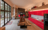 Modern home with Dining Room, Bench, Table, Desk, Accent Lighting, and Wood Burning Fireplace. The great room is 22'x44', so specifying structural insulated panels (SIPs) for the roof was a logical choice for the designers. This resulted in unobstructed ceiling spans, as the structure (fabricated laminated splines) are incorporated inside the insulated panel joints.
The structural insulated panels (SIPs) for the walls and roof were prefabed in a local Washington factory, delivered to the site and erected in less than five days. The house was weatherproof, including doors and windows in a week.
A glossy Ferrari-red kitchen is topped off with high-end economy size appliances, recessed LED strip lighting bringing into play both form and function. On the platform above the kitchen a series of glass vessels by artist John deWit and a Ferrari pedal car are displayed. Photo 3 of The Barn Gallery