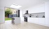 Modern home with Kitchen, Engineered Quartz Counter, White Cabinet, Recessed Lighting, Pendant Lighting, Cooktops, Undermount Sink, Range Hood, Wall Oven, and Light Hardwood Floor. This spacious kitchen was designed for simplicity and functionality. Black and white kitchens that incorporate elements of gray tend to have a softer look. Seen here, gray accents, like the pendant lights and backsplash color, abound. Says the architect, "The design of the interior achieves a softer touch by using bespoke detailing and a rich palette of materials such as stone and timber." Photo of SW House