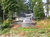 Modern home with Outdoor, Front Yard, Trees, Shrubs, Grass, Hardscapes, Large Patio, Porch, Deck, Wood Patio, Porch, Deck, and Retaining Fences, Wall. Front Home and Decks with pathways down to beach Photo 3 of Cortes Island Custom Blu Prefab
