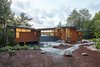 Modern home with Exterior, Beach House Building Type, House, Metal Roof Material, Wood Siding Material, Butterfly RoofLine, and Cabin Building Type. Entrance side view surrounded by landscapes and lake Photo of Stanley Bay House