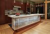 Modern home with Kitchen, Glass Tile Backsplashe, Engineered Quartz Counter, Wall Oven, Light Hardwood Floor, Cooktops, Ceiling Lighting, Pendant Lighting, Refrigerator, Wood Cabinet, and Undermount Sink. View of kitchen with suspended glass cabinet at island Photo 8 of DESCHUTES House
