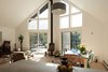 Modern home with Living Room, Coffee Tables, Wood Burning Fireplace, Ceiling Lighting, Chair, and Light Hardwood Floor. Living/Dining room. Flanked by a view into the tree crowns, rests the centerpiece, a cast-iron wood burning stove by the danish manufacturer Morso. The Hard Maple floors are finished with MonoCoat Smoke oil to enhance its pale hue. An old chemistry lab table has been repurposed as dining table. Photo of Country House With a Modern Edge