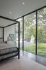 Modern home with Ceiling Lighting, Recessed Lighting, and Dark Hardwood Floor. Within each bedroom, the architecture acts as a frame to the landscape beyond. The opening picture faces north towards a sculpted landscape of Japanese maples and native grasses; it is 10' h x 20' w. The stone embedded in the landscape came from the excavated bedrock when construction the home. The colors within each bedroom were selected to compliment the species of plants outside the home. Photo 13 of The Winnwood Residence