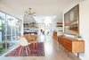 Modern home with Dining Room, Chair, Storage, Table, Light Hardwood Floor, Ceiling Lighting, and Rug Floor. Dining Room Looking into Kitchen and Family Room Photo 2 of Midcentury Dream House