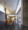 Modern home with Kitchen, Metal Counter, Microwave, Refrigerator, Wall Oven, Ceiling Lighting, Range Hood, Cooktops, Dishwasher, Concrete Floor, Engineered Quartz Counter, Wood Cabinet, Glass Tile Backsplashe, Pendant Lighting, and Undermount Sink. Double height kitchen with the warm mass of cabinets rising like a stalagmite in the cavern scaling the height while the hung pendant lights from ceiling coming down like stalactites to the human scale. Photo 4 of Essence of the Desert
