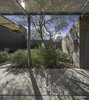 Modern home with Outdoor, Concrete Fences, Wall, Large Patio, Porch, Deck, Trees, Metal Patio, Porch, Deck, Landscape Lighting, Post Lighting, and Back Yard. Concrete stem wall mutates and rises to give birth to the window composition. The notch in the masonry fence wall receives the setting sun of the owners' marriage anniversary. Photo 16 of Essence of the Desert