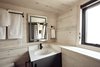 The pine ledge wraps around creating useful storage. Integrated linen nooks can be seen in the lighted mirror's reflection. The bathroom features a one-piece toilet, 30x60 tub and Kohler wall surrounds. Photo 18 of Land Ark RV - Drake modern home