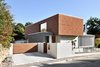 Modern home with Exterior, House Building Type, Wood Siding Material, Flat RoofLine, Glass Siding Material, Stucco Siding Material, and Concrete Siding Material. Exterior view from the street. Moveable aluminium louvers provide privacy and direct sunlight into the living room area. Photo 3 of House KI