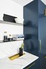 Modern home with Kitchen, Drop In Sink, Marble Counter, Beverage Center, Colorful Cabinet, Marble Backsplashe, Light Hardwood Floor, and Cooktops. The kitchen features flat blue cabinets with floating shelves and marble-look countertops. Photo 6 of Seaholm Custom Condo