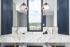 Modern home with Bath Room, Marble Counter, Ceramic Tile Floor, Open Shower, Drop In Sink, and Pendant Lighting. The master bathroom is designed with Carrara marble counters, blue cabinets and brass hardware sinks. Photo 12 of Seaholm Custom Condo
