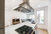 Modern home with Kitchen, Range, Wine Cooler, Light Hardwood Floor, Dishwasher, Range Hood, Cooktops, Colorful Cabinet, Refrigerator, Undermount Sink, Granite Counter, and Ceiling Lighting. Kitchen towards rear Photo 16 of The Doyle Residence