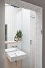 Modern home with Bath Room, Wood Counter, Wall Mount Sink, Wall Lighting, Ceramic Tile Wall, and Open Shower. The ensuite is finished in continuous floor to ceiling tiles to emphasise the feeling of space Photo 8 of Hackney Mews House