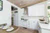 Modern home with Kitchen, Light Hardwood Floor, White Cabinet, Ceramic Tile Backsplashe, Undermount Sink, Pendant Lighting, and Engineered Quartz Counter. The kitchen includes a stainless steel Summit Appliance® range, dishwasher, and a 30” refrigerator with enough room for a 6-person dining table. Photo 2 of Saltbox Tiny Home