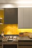 Modern home with Kitchen, Ceramic Tile Backsplashe, Accent Lighting, Range, Recessed Lighting, White Cabinet, Metal Cabinet, Granite Counter, Light Hardwood Floor, and Range Hood. In the kitchen, the designers also considered lighting design with cabinet lighting both under and above the cabinets. The backsplash tile is by Fireclay Tile. The hood range is custom wrapped in blackened steel by Joe Chambers. Photo 10 of Balboa Residence