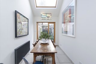 Glazed French doors, elevated ceilings, and a large skylight allow the light to flow through and illuminate the dining area.