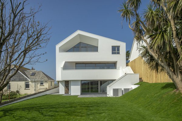 The first-floor balcony is accessed via the living room, and externally via a staircase that leads to the garden. The simplicity of the white exterior reflects a relaxed, seaside vibe.