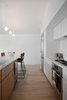 Modern home with Kitchen, Stone Slab Backsplashe, White Cabinet, Dishwasher, Drop In Sink, Light Hardwood Floor, Pendant Lighting, Range Hood, Marble Counter, Refrigerator, and Wood Cabinet. The kitchen features custom wood cabinetry with marble countertops & backsplash, stainless steel Bosch appliances and a deep under-mounted stone sink. Photo 7 of Raber By VEIN