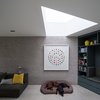 Modern home with Living Room, Bookcase, and Concrete Floor. A wedge-shaped skylight allows natural light to suffuse the interiors. The architects preserved a palette of dark, natural materials on the ground floor. Photo of Oatlands