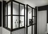 Modern home with Bath Room, Subway Tile Wall, and Enclosed Shower. In the industrial-feeling master bath, we replaced the existing tub with a larger, iron-and-glass shower, which features handmade white subway tiles. Brass mirrors hang over the new double vanity, which includes storage space underneath. Photo 10 of Renovated SoHo Duplex