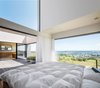 Modern home with Bedroom and Bed. The master bedroom ceiling is 13 feet high and tilted to 29 degrees. When opened, the homeowners are able to sleep in the open air. Their request to the architect was that they be able to stargaze before falling asleep. Photo 4 of Where the Eagles Live