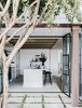 Modern home with Kitchen, Stone Tile Backsplashe, White Cabinet, Medium Hardwood Floor, Wall Lighting, Marble Counter, Range, and Drop In Sink. View to Kitchen from Courtyard Photo 2 of Palm Beach House