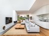 Modern home with Living Room, Corner Fireplace, Sofa, Gas Burning Fireplace, Chair, Medium Hardwood Floor, Bench, Ottomans, and Ceiling Lighting. The open living, dining and kitchen space opens out on to the rear garden. Photo 16 of Cloud House