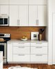 Modern home with Kitchen, Rug Floor, Range, Medium Hardwood Floor, Microwave, Wood Backsplashe, Wood Cabinet, Engineered Quartz Counter, and White Cabinet. View of kitchen cabinets by Low Design Office Photo 9 of Guadalupe River House