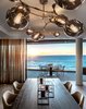 Modern home with Dining Room, Chair, Pendant Lighting, Table, and Light Hardwood Floor. The Bison dining table is topped with Lab series candle holders in brass and surrounded by Tofu dining chairs. On the balcony, a custom granite topped table looks out over a panoramic stretch of Atlantic Ocean. Photo 9 of Clifton 301