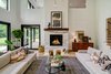 Modern home with Living Room, End Tables, Lamps, Table Lighting, Console Tables, Ottomans, Accent Lighting, Coffee Tables, Sofa, Gas Burning Fireplace, Light Hardwood Floor, Standard Layout Fireplace, Ceiling Lighting, and Stools. Dorchester Interior Great Room Photo 9 of The Dorchester Project by Paul + Jo Studio