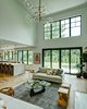 Modern home with Living Room, Sofa, Lamps, Console Tables, Light Hardwood Floor, Stools, Ottomans, Standard Layout Fireplace, Coffee Tables, End Tables, Ceiling Lighting, Accent Lighting, Table Lighting, and Gas Burning Fireplace. Dorchester Interior Great Room/Kitchen Photo 10 of The Dorchester Project by Paul + Jo Studio