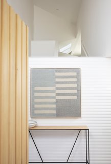 Cedar siding, painted white, wraps around the stairwell on all four sides, echoing the exterior of the home.