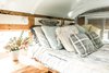 Modern home with Bedroom, Medium Hardwood Floor, and Bed. Our bedroom area is simple and cozy. The two built ins you see on either end of the bed to the left house our bathroom elements, one is our composting toilet the other is our tub base/shower. The wooden tops flip up when in use. Photo 6 of The Wild Drive Life Bus
