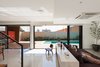 Modern home with Living Room, Ceiling Lighting, Bookcase, Chair, Sofa, and Ceramic Tile Floor. Sliding glass doors integrate internal and exterior spaces, allowing a full use of the terrain. Photo 7 of QP House