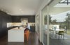 Modern home with Kitchen, Microwave, Dishwasher, Range, Refrigerator, Dark Hardwood Floor, Ceiling Lighting, Beverage Center, Laminate Cabinet, Recessed Lighting, Range Hood, Colorful Cabinet, Undermount Sink, Stone Slab Backsplashe, Bamboo Floor, and Engineered Quartz Counter. From the living-dining area the kitchen caps the main space reinforcing the inside-outside connection to the deck and it's view. Photo 6 of Farwell