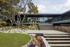 Modern home with Outdoor, Stone Fences, Wall, Gardens, Shrubs, Garden, Metal Patio, Porch, Deck, Trees, Grass, Hardscapes, Walkways, Pavers Patio, Porch, Deck, Decking Patio, Porch, Deck, Large Patio, Porch, Deck, Boulders, Concrete Patio, Porch, Deck, Front Yard, and Hanging Lighting. A natural, stacked-stone fin is the grounding element below the cantilevered bedroom wing. Photo 4 of Moat's Corner