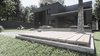 Modern home with Outdoor, Concrete Patio, Porch, Deck, Grass, Back Yard, Stone Patio, Porch, Deck, Hardscapes, Wood Patio, Porch, Deck, and Large Patio, Porch, Deck. Materials alternating from the main facade are also present here - wooden striped podiums and stone square stairs. Photo 13 of The Grey House